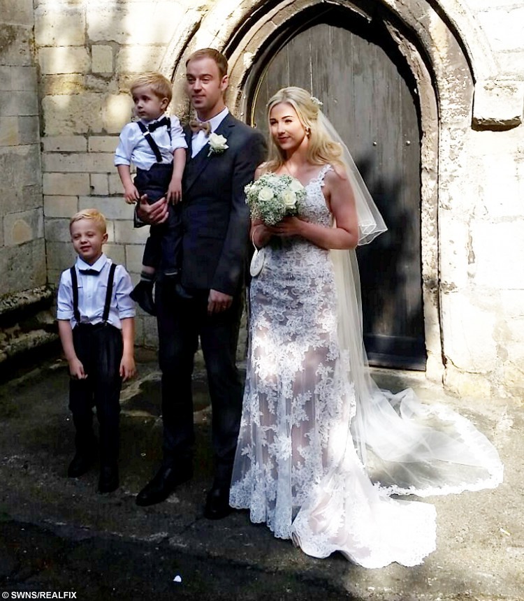 Emma Scarborough and her husband Jamie on their wedding day. See SWNS story SWSELFIE; A bride was delighted when the vicar at her wedding unexpectedly interrupted the ceremony - to take a SELFIE. Emma Scarborough, 26, had just met her husband-to-be Jamie, 28, at the head of the church when the vicar said he had something to do before he married them. Vicar Paul Frost pulled out a selfie stick and much to the amusement of the guests at St John's Anglican church snapped an amazing photo of the grinning wedding party. It is thought to be the first ever vicar wedding selfie using a selfie stick.